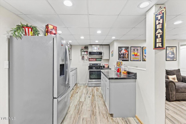 kitchen featuring dark countertops, light wood finished floors, a drop ceiling, recessed lighting, and appliances with stainless steel finishes