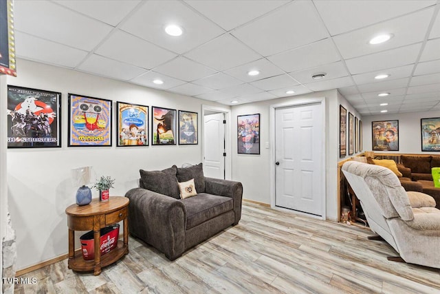 living room with recessed lighting, a drop ceiling, baseboards, and light wood finished floors