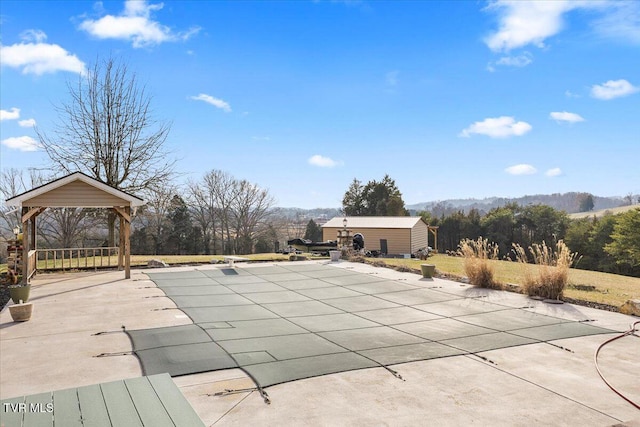 view of swimming pool with a gazebo, an outbuilding, and a patio