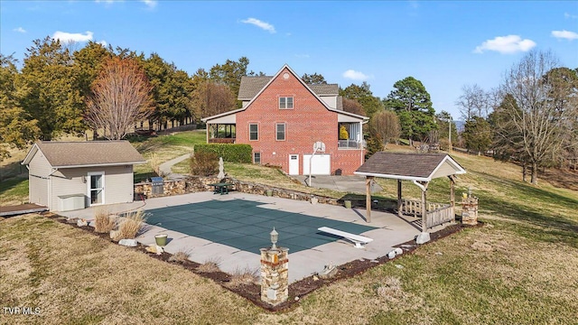 back of house featuring a covered pool, a patio, a lawn, and an outbuilding