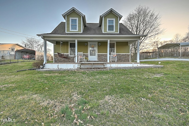 cape cod home with a detached carport, fence, a front lawn, and stone siding