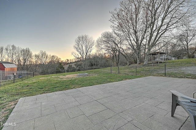 patio terrace at dusk featuring a lawn and a fenced backyard