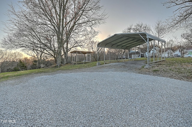 parking at dusk with gravel driveway and a carport