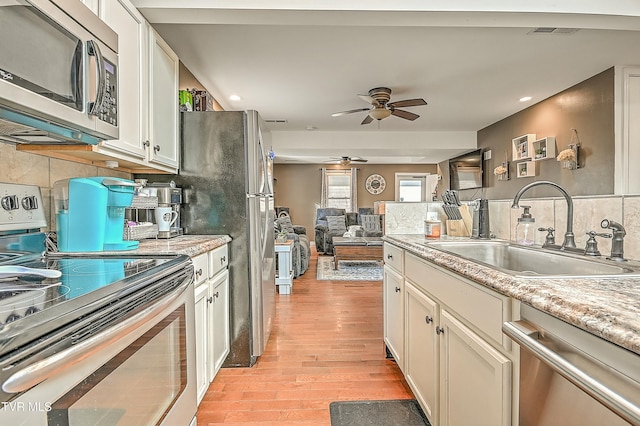 kitchen with visible vents, a ceiling fan, a sink, backsplash, and appliances with stainless steel finishes