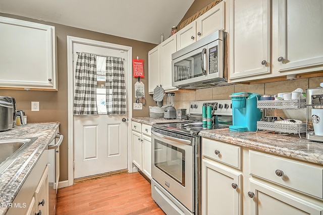 kitchen featuring light wood-type flooring, stainless steel appliances, light stone counters, and tasteful backsplash