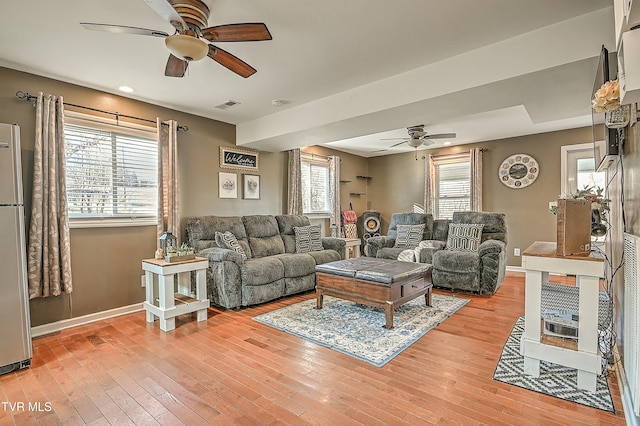 living area with baseboards, a ceiling fan, visible vents, and light wood-type flooring