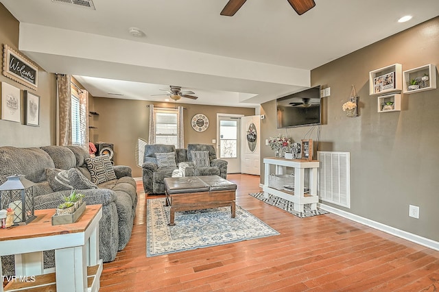 living area with visible vents, baseboards, ceiling fan, and wood finished floors