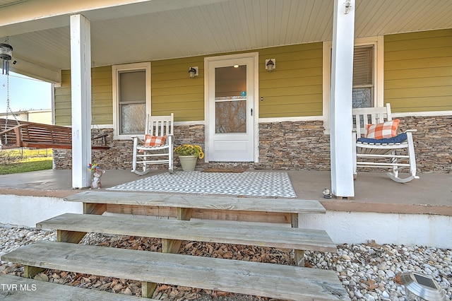 view of exterior entry with stone siding and a porch