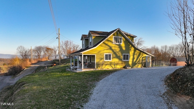 view of property exterior featuring gravel driveway, a yard, and fence