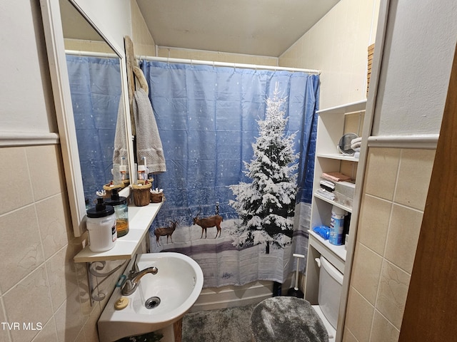 bathroom with a sink, tile walls, a shower with curtain, and wainscoting