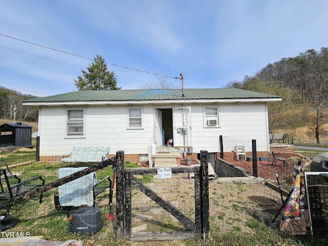 view of front of home featuring metal roof, cooling unit, a fenced front yard, and a gate