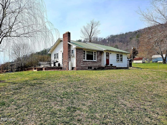 view of front of property with metal roof, a chimney, and a front lawn