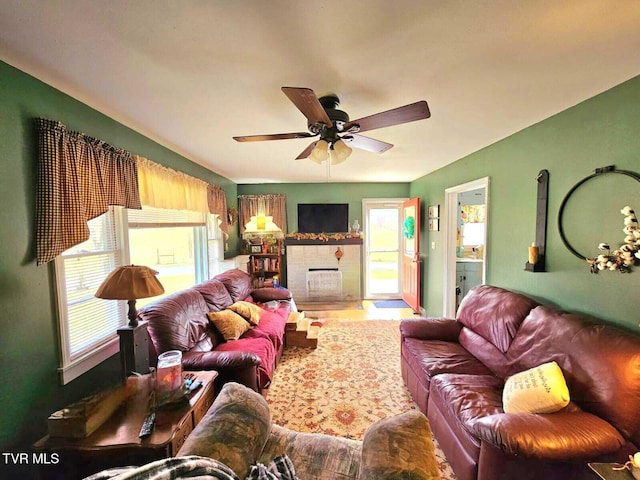 living room featuring a tiled fireplace and a ceiling fan