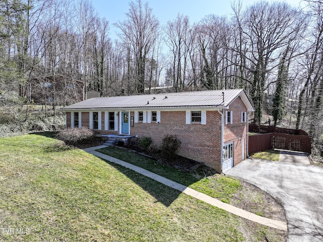 view of front facade featuring brick siding, aphalt driveway, a front yard, a chimney, and a garage