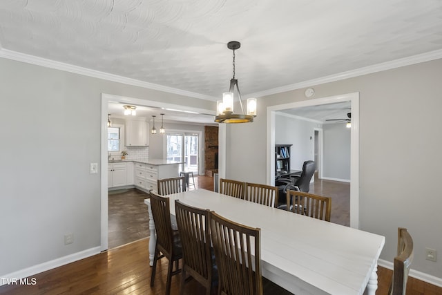 dining room with ornamental molding, dark wood-style floors, baseboards, and ceiling fan