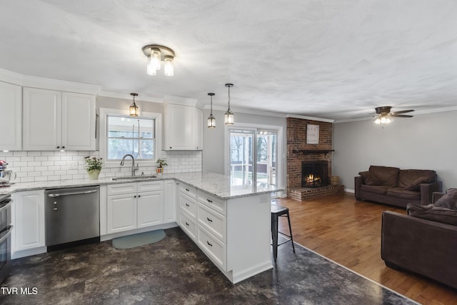 kitchen featuring a sink, a kitchen breakfast bar, open floor plan, a peninsula, and dishwasher