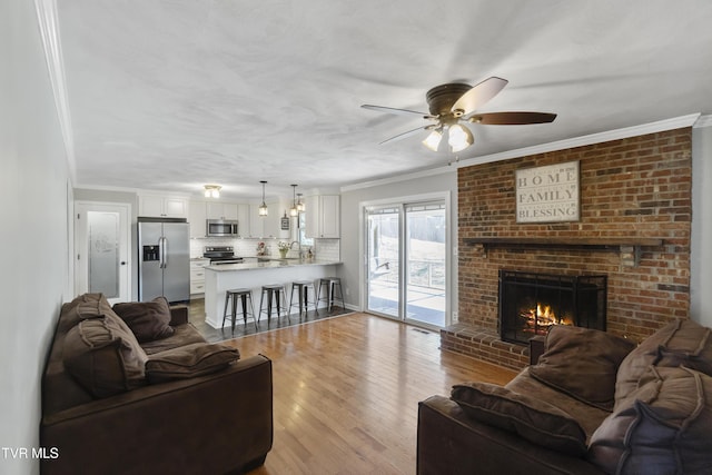 living area featuring crown molding, a fireplace, wood finished floors, a textured ceiling, and a ceiling fan