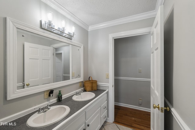 bathroom featuring a sink, a textured ceiling, ornamental molding, and double vanity