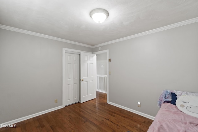 unfurnished bedroom featuring crown molding, wood finished floors, and baseboards