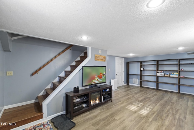 living area with visible vents, a textured ceiling, wood finished floors, and stairway