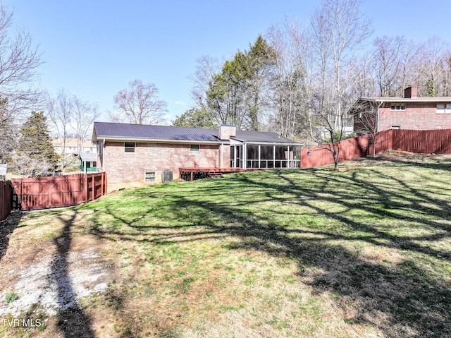 back of property with a lawn, a fenced backyard, cooling unit, a sunroom, and brick siding