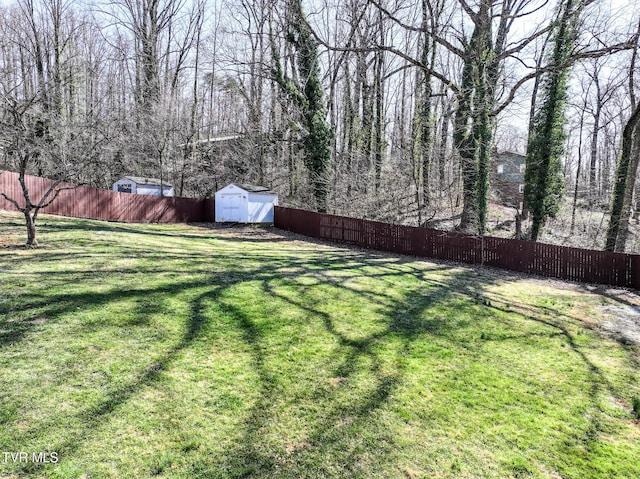 view of yard with a storage shed, an outbuilding, and a fenced backyard