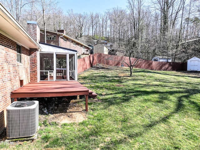 view of yard featuring a shed, central AC unit, a fenced backyard, a sunroom, and an outbuilding