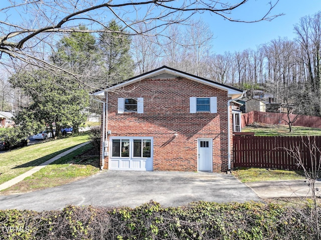 view of side of property with fence, brick siding, and a lawn