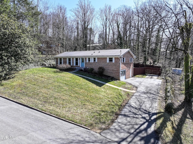 ranch-style house with a front lawn, aphalt driveway, fence, a garage, and brick siding