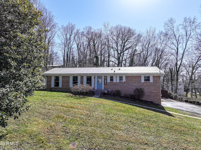 view of front of house with brick siding, metal roof, and a front yard