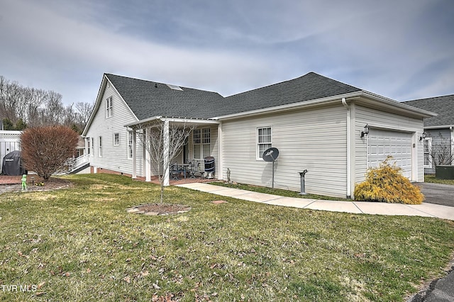 view of side of property featuring a garage, a yard, a shingled roof, and aphalt driveway