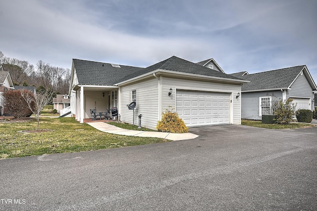 view of side of home featuring aphalt driveway, a yard, and an attached garage