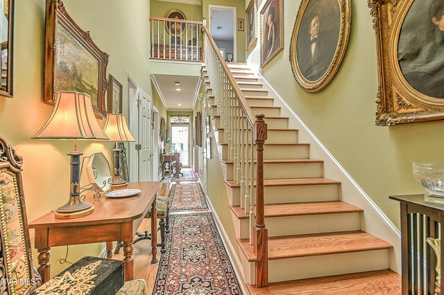 stairs featuring wood finished floors and a towering ceiling