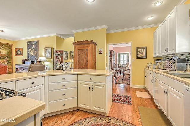 kitchen featuring dishwasher, light countertops, light wood-style floors, and crown molding