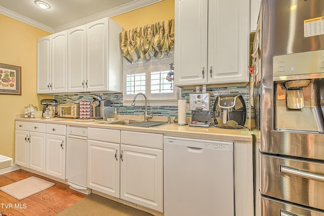 kitchen with a sink, stainless steel appliances, tasteful backsplash, and white cabinets