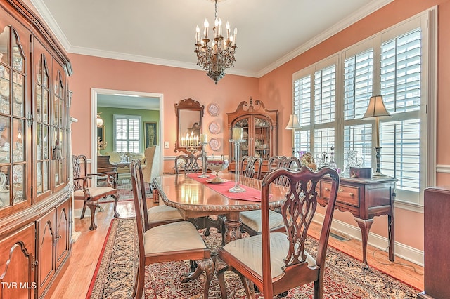 dining space with a chandelier, light wood-style flooring, crown molding, and baseboards