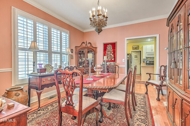 dining area featuring a notable chandelier, a healthy amount of sunlight, and ornamental molding