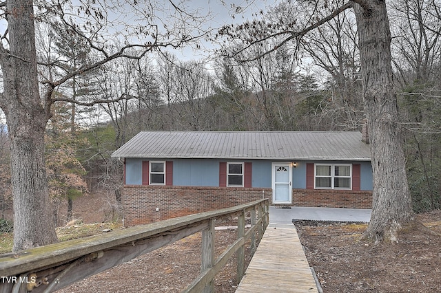 single story home featuring brick siding and metal roof