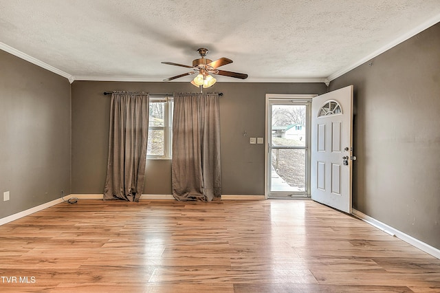 foyer entrance featuring light wood-style flooring, ornamental molding, a healthy amount of sunlight, and ceiling fan