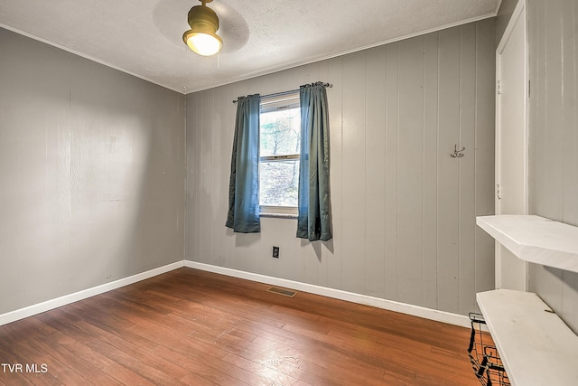 spare room featuring hardwood / wood-style floors, baseboards, visible vents, and a textured ceiling