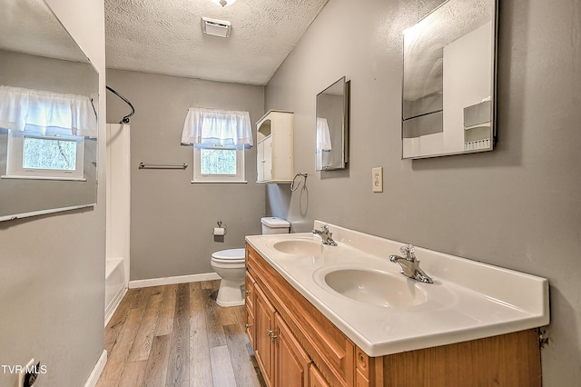 bathroom with toilet, wood finished floors, visible vents, and a sink