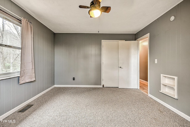 unfurnished bedroom featuring visible vents, a ceiling fan, carpet, and baseboards