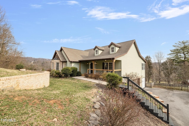 view of front of home with a front yard, roof with shingles, a porch, a garage, and aphalt driveway