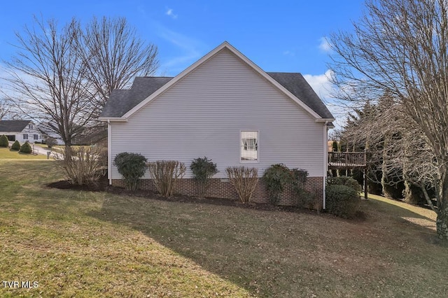 view of home's exterior featuring a deck, a shingled roof, and a yard