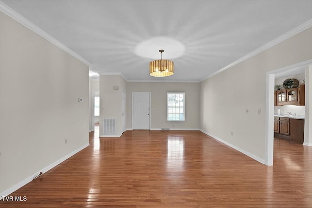 interior space with crown molding, visible vents, light wood-type flooring, and baseboards