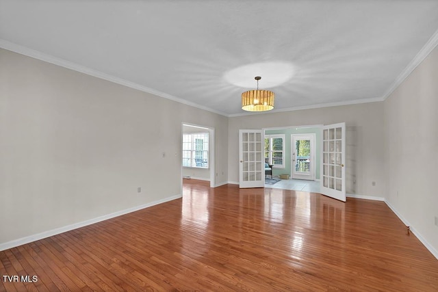 unfurnished room featuring crown molding, french doors, baseboards, and wood-type flooring