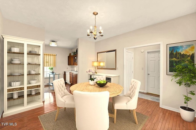 dining space with a chandelier, baseboards, and wood-type flooring