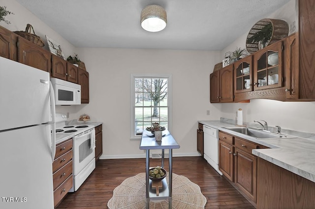 kitchen featuring dark wood-style flooring, white appliances, glass insert cabinets, and a sink