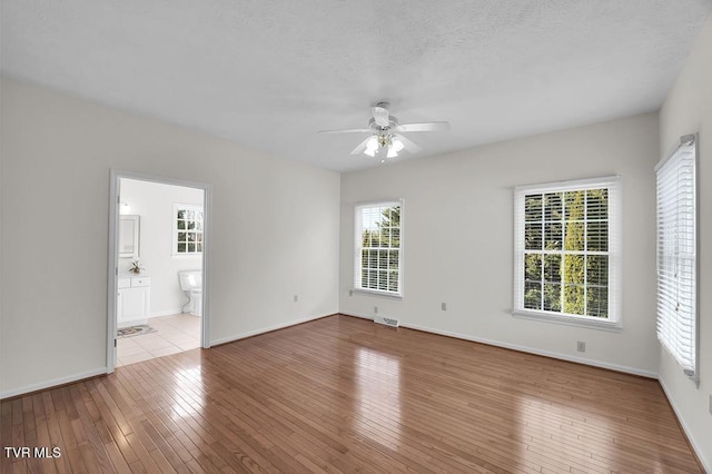 spare room with hardwood / wood-style flooring, baseboards, visible vents, and ceiling fan