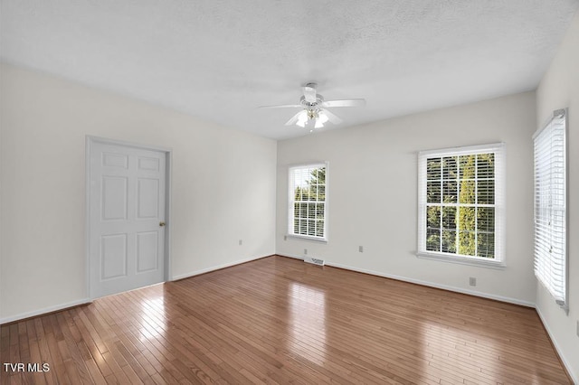 unfurnished room with visible vents, a textured ceiling, hardwood / wood-style floors, and a ceiling fan